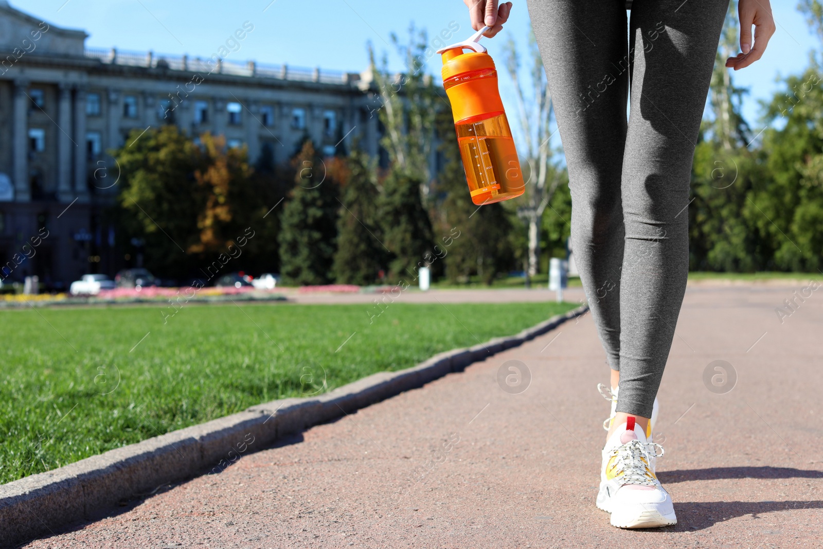 Photo of Young woman holding bottle with clean water on street. Space for text