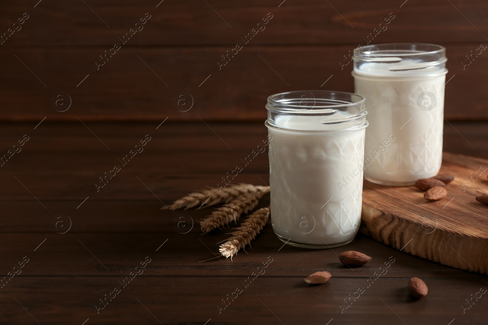 Photo of Jars with milk and nuts on wooden background