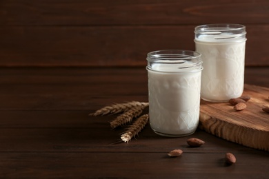 Jars with milk and nuts on wooden background