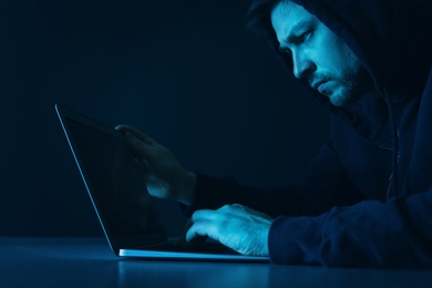 Photo of Man using laptop in dark room. Criminal offence