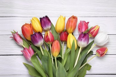 Photo of Beautiful colorful tulip flowers on white wooden table, top view