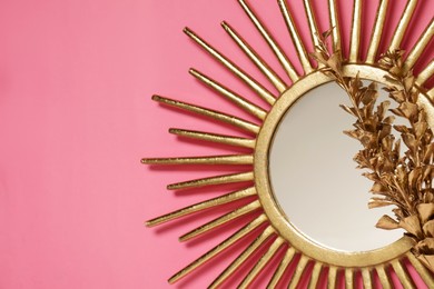 Golden mirror and dried flower on pink background, top view. Space for text