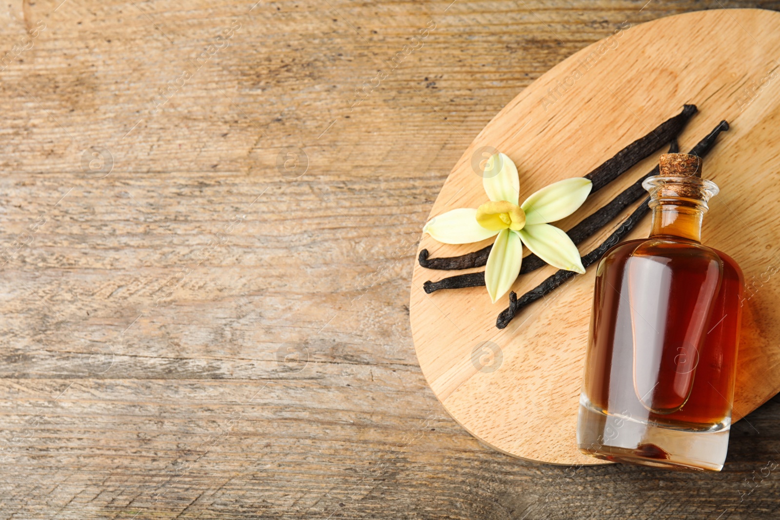 Photo of Flat lay composition with vanilla extract on wooden table. Space for text