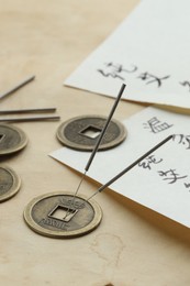 Photo of Acupuncture needles, Chinese coins and sheets with characters on paper, closeup