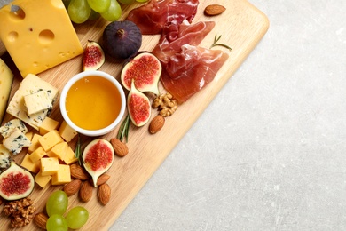 Set of different snacks with ripe figs served on light table, top view. Space for text