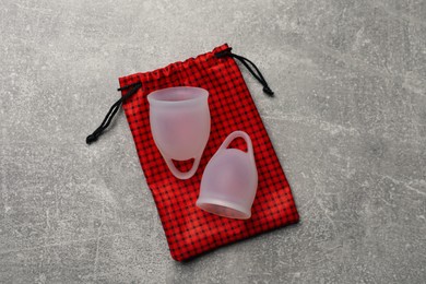 Menstrual cups and cotton bag on grey background, top view. Reusable feminine hygiene product