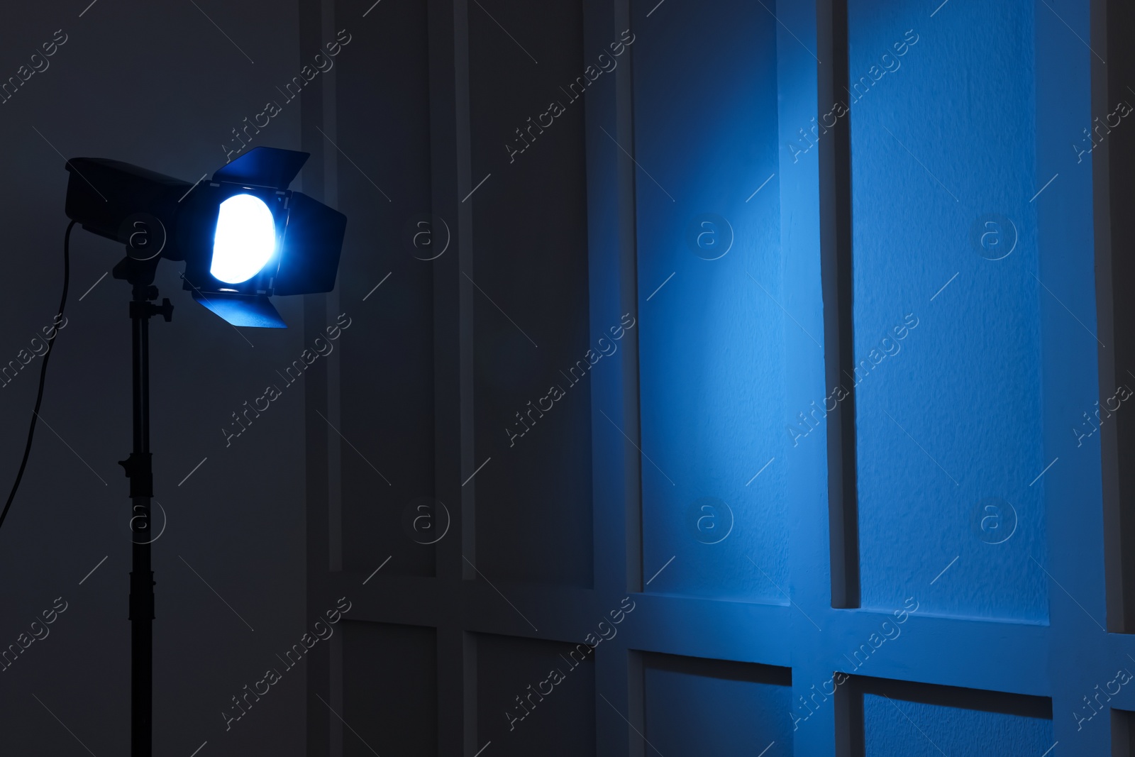 Photo of Bright blue spotlight near wall indoors, space for text