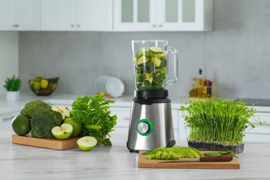 Photo of Blender with ingredients for smoothie and products on white marble table in kitchen