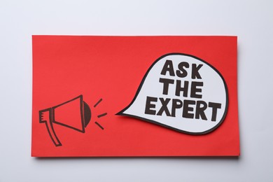 Photo of Red card with drawn loudspeaker and phrase Ask The Expert on light background, top view