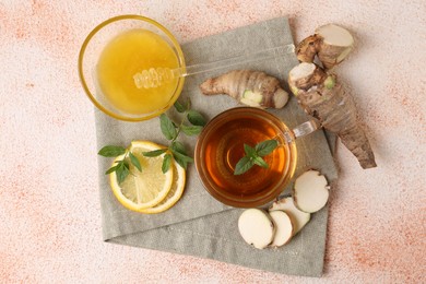 Photo of Flat lay composition of tea with mint, honey, lemon and ginger on beige textured table