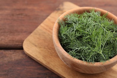 Bowl of fresh dill on wooden table, space for text