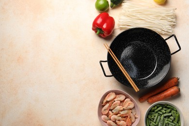 Photo of Black wok, chopsticks and products on color textured table, flat lay. Space for text