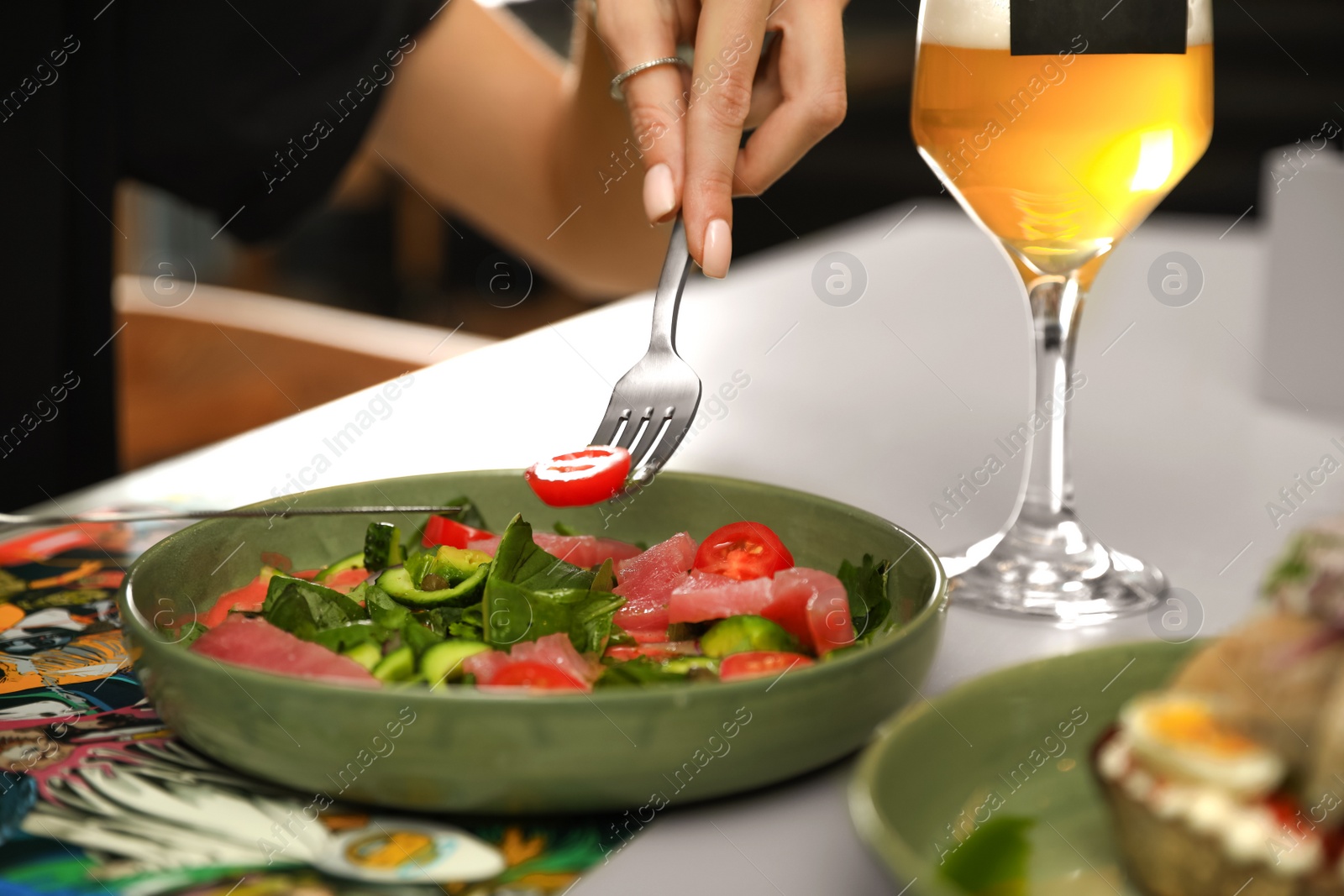 Photo of Young woman with tasty salad and glass of beer at table, closeup