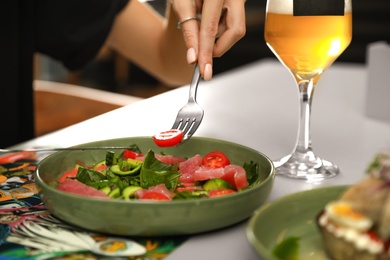 Young woman with tasty salad and glass of beer at table, closeup