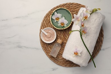 Composition with different spa products and flowers on white marble table, top view. Space for text