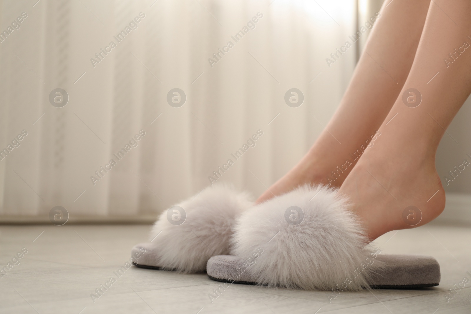 Photo of Woman in fuzzy slippers at home, closeup. Space for text