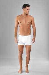 Handsome man in white underwear on light grey background