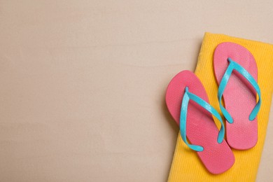 Photo of Pair of pink flip flops and blanket on sand, top view. Space for text