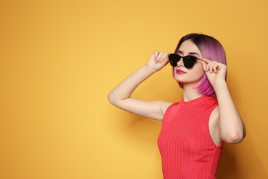 Photo of Young woman with trendy hairstyle wearing sunglasses against color background