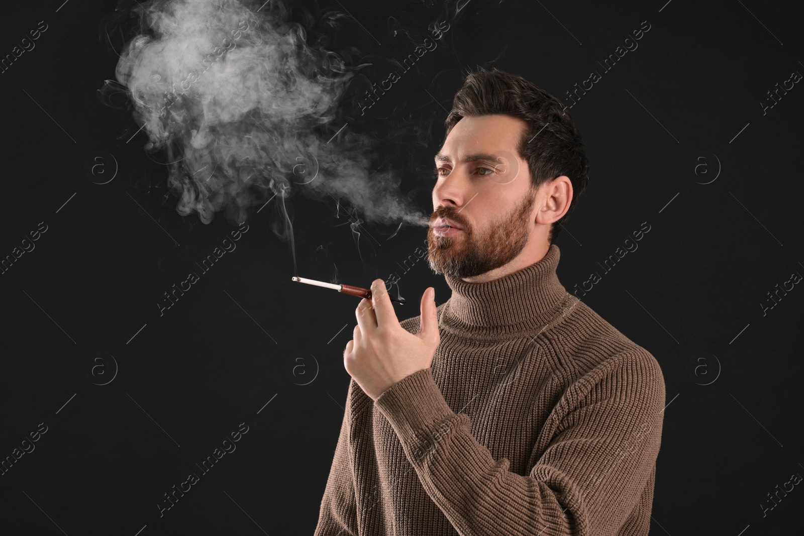 Photo of Man using cigarette holder for smoking on black background, space for text