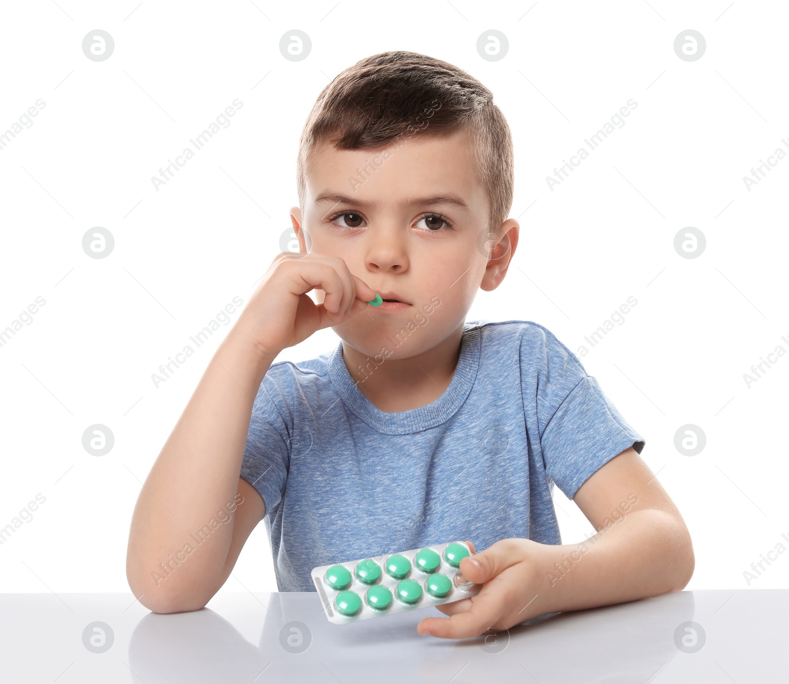 Photo of Little child taking pill on white background. Household danger