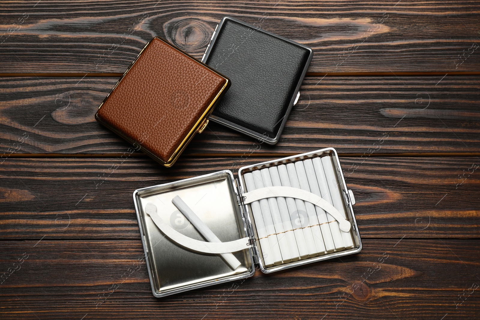 Photo of Leather cigarette cases on wooden table, flat lay