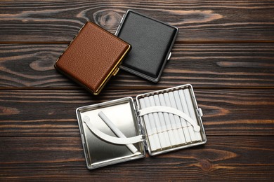 Photo of Leather cigarette cases on wooden table, flat lay