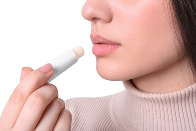 Photo of Young woman applying cold sore balm on lips against white background, closeup