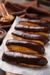Photo of Delicious eclairs covered with chocolate on table