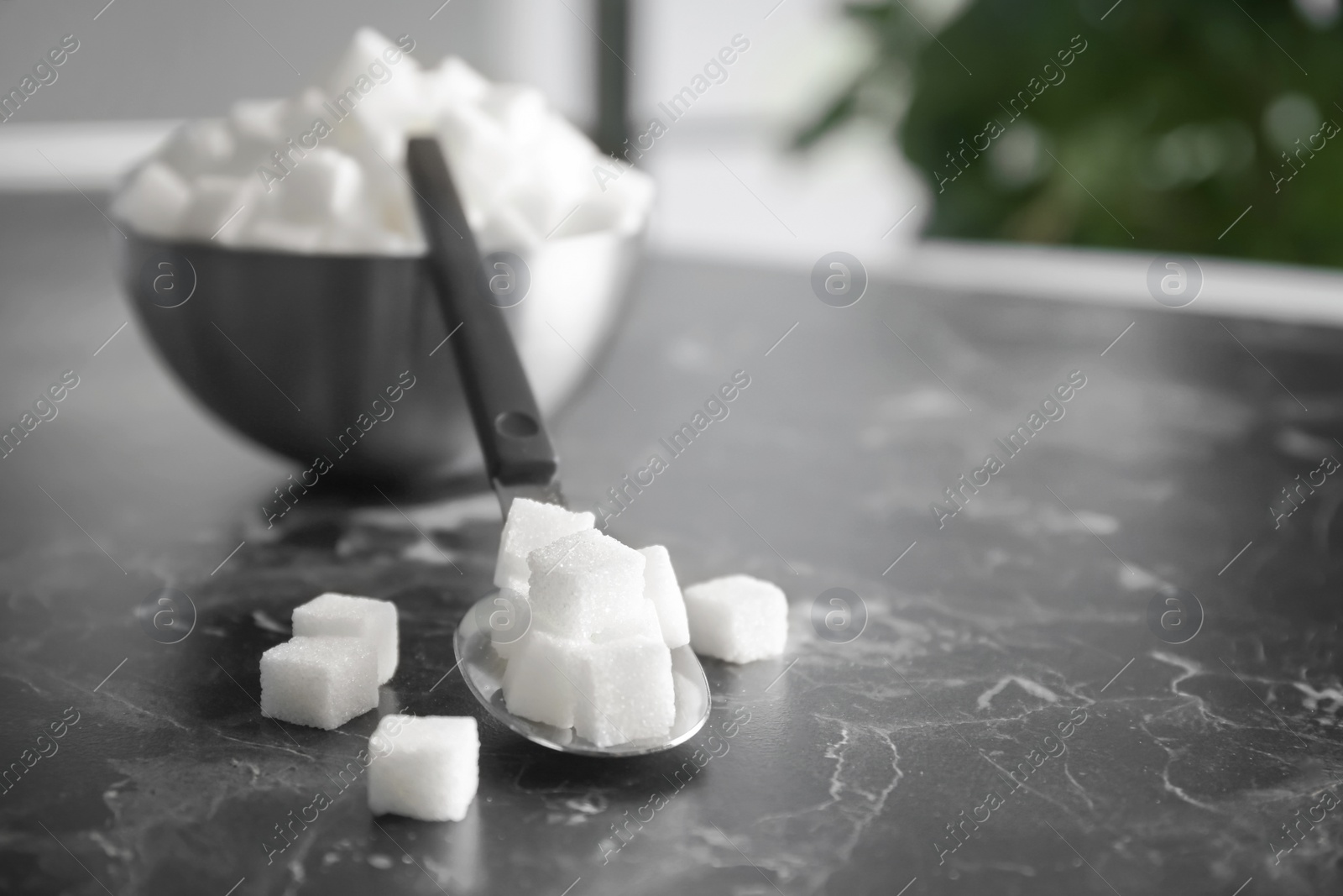 Photo of Spoon and bowl with refined sugar on table
