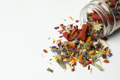 Photo of Overturned glass jar with dry herbal tea on white background, closeup. Space for text