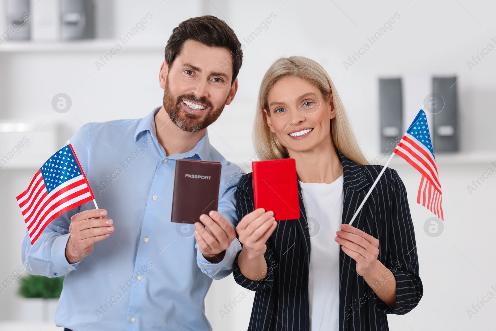 Photo of Immigration. Happy couple with passports and American flags indoors