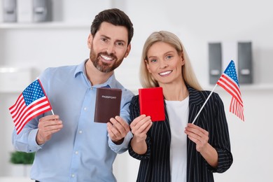 Immigration. Happy couple with passports and American flags indoors