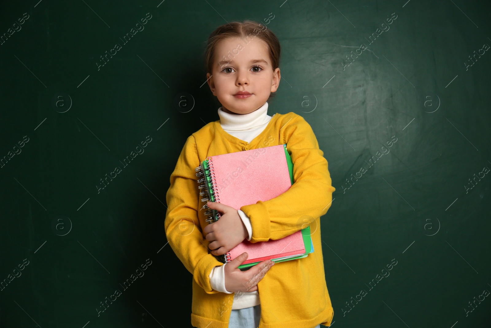 Photo of Cute little child near chalkboard. First time at school