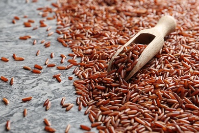Brown rice and scoop on grunge background, closeup view