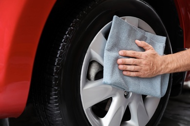 Man cleaning automobile wheel with duster, closeup. Car wash service