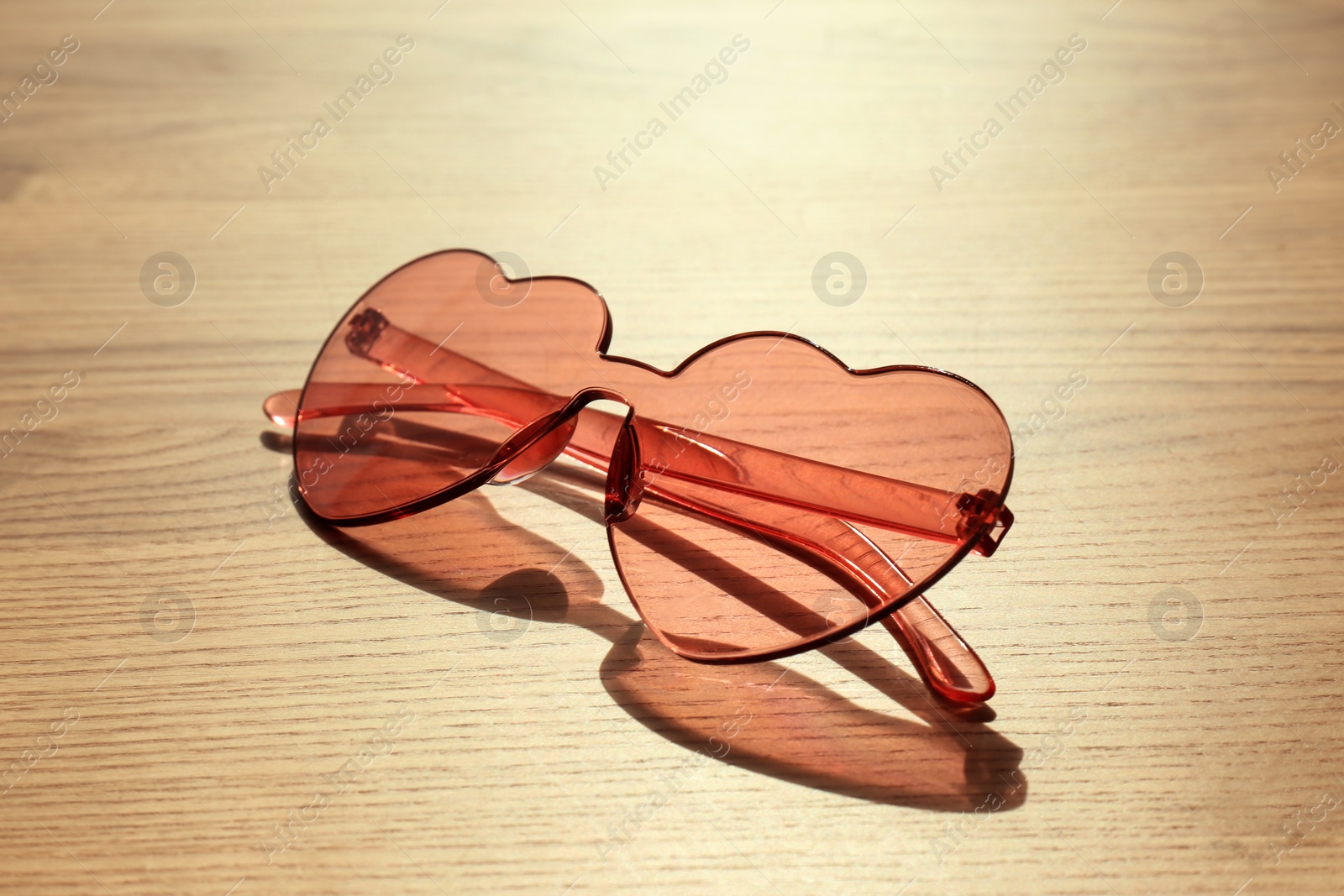 Photo of Stylish heart shaped sunglasses on wooden background