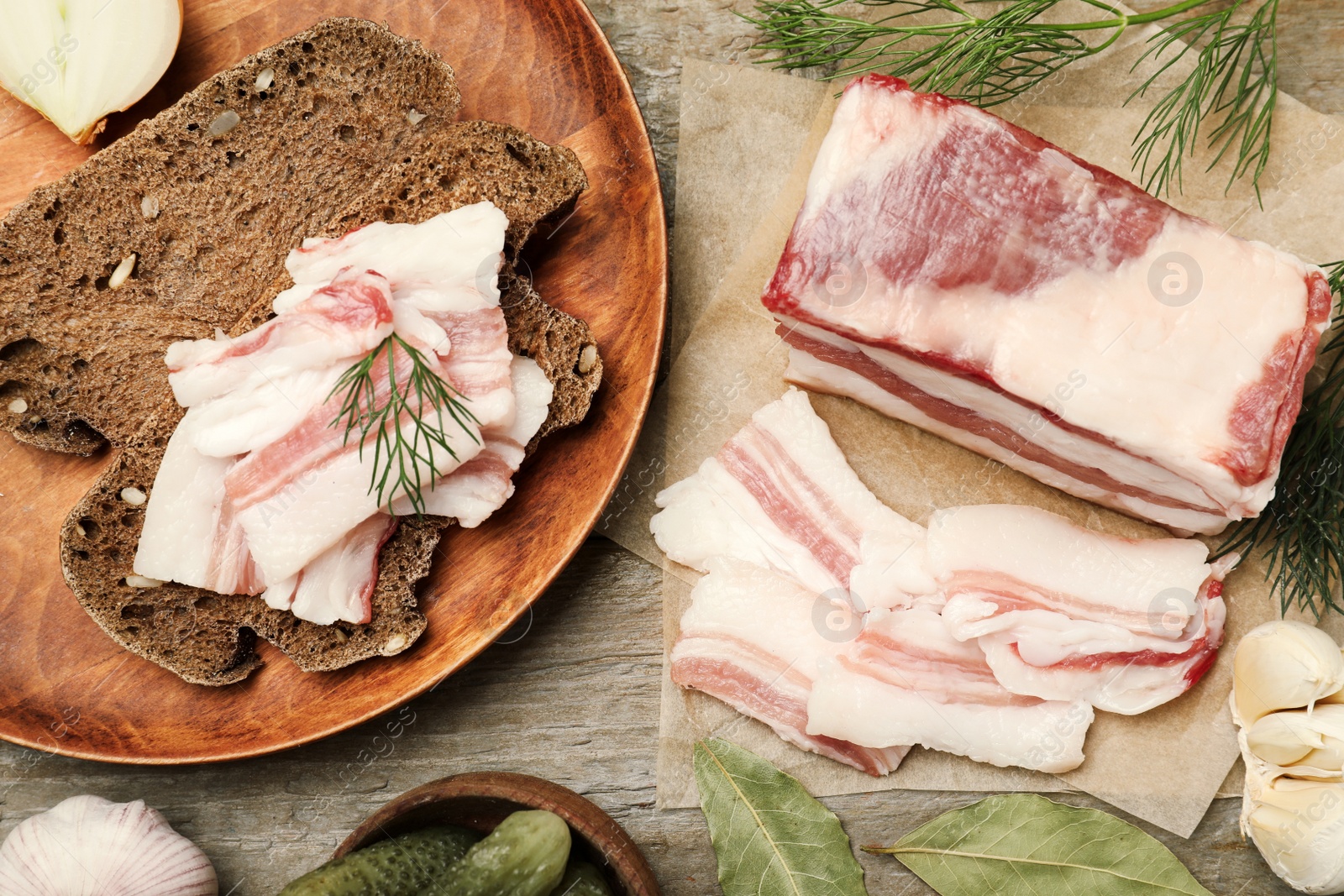 Photo of Tasty salt pork with rye bread and dill on wooden table, flat lay