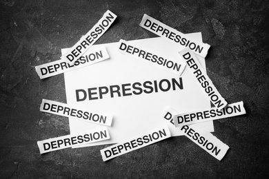 Photo of Many papers with words Depression on dark background, top view