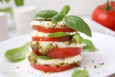 Photo of Stacked Caprese salad with pesto sauce on plate, closeup