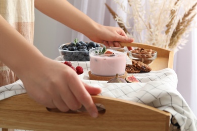 Photo of Woman holding wooden tray with delicious breakfast and fig smoothie, closeup
