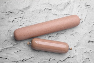 Photo of Delicious liver sausages on white textured table, flat lay