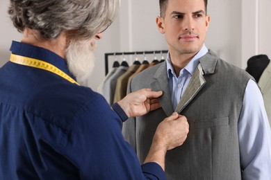 Photo of Professional tailor working with client in atelier