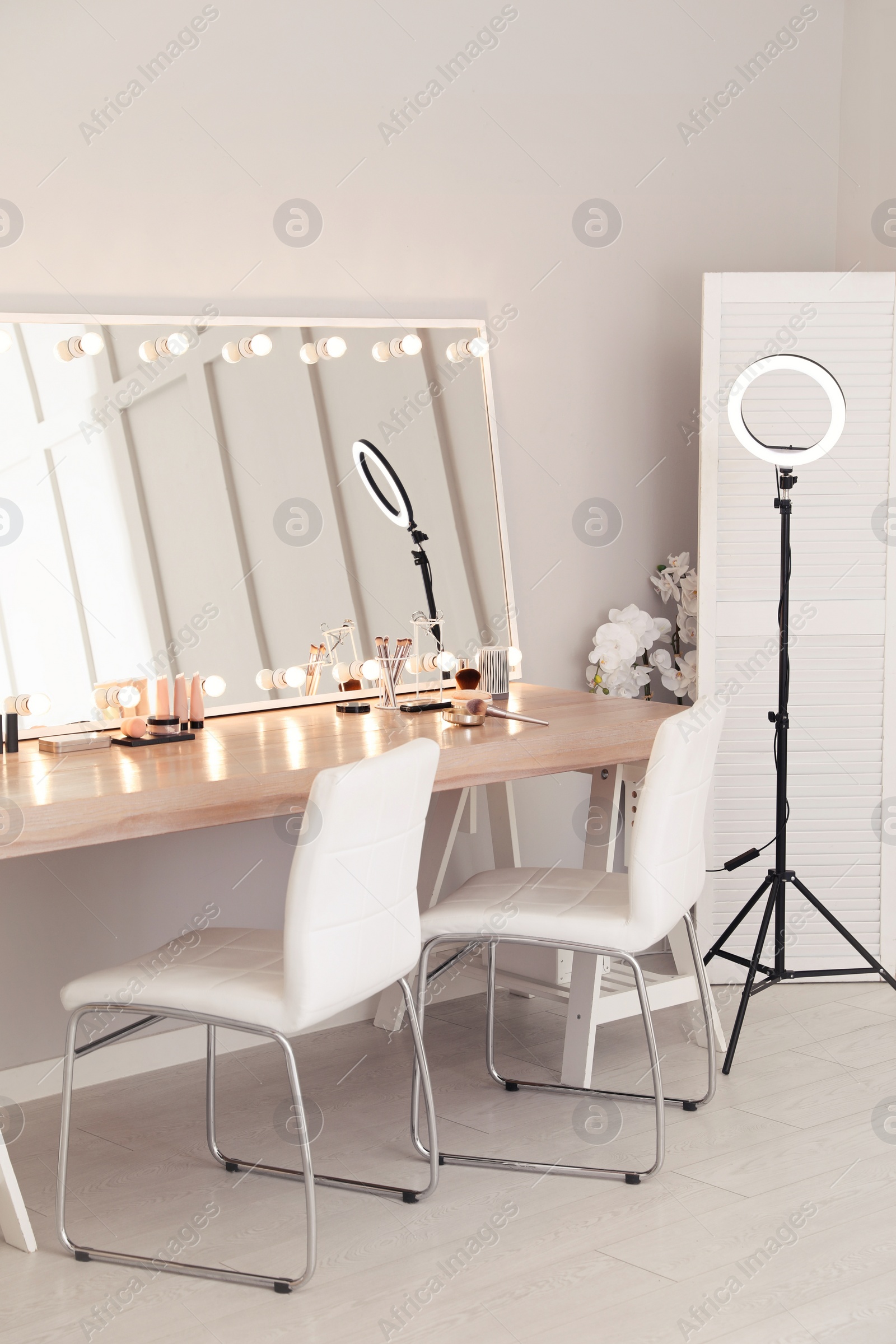 Photo of Modern mirror with light bulbs on dressing table in makeup room