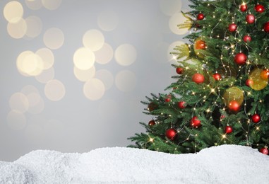 Image of Beautifully decorated Christmas tree and snow on light background, space for text. Bokeh effect