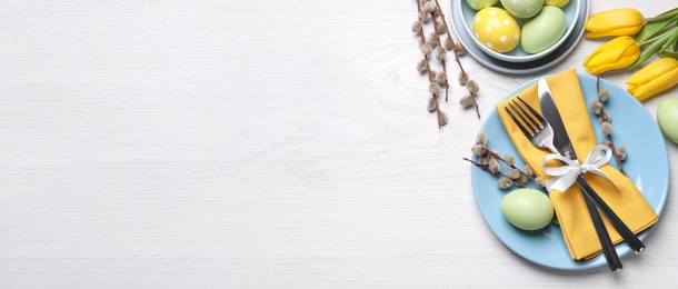 Image of Festive Easter table setting with eggs on white wooden background, flat lay. Space for text