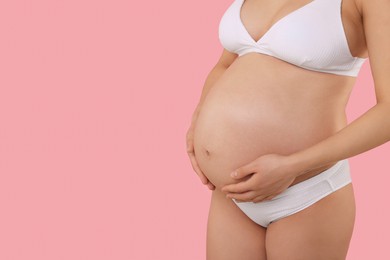 Pregnant woman in stylish comfortable underwear on pink background, closeup. Space for text