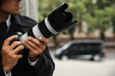 Photo of Private detective with modern camera spying on city street, closeup