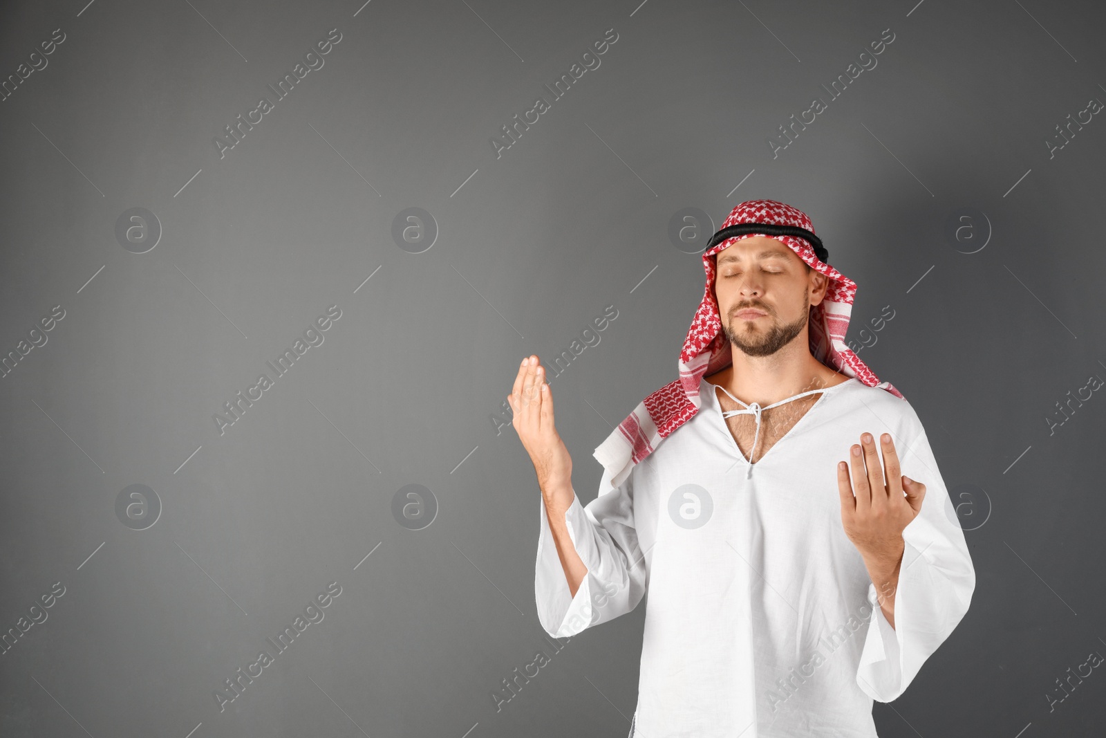 Photo of Muslim man praying on gray background. Space for text