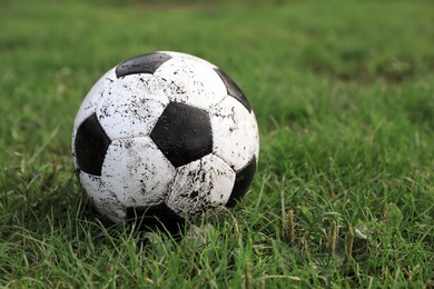 Photo of Dirty soccer ball on green grass outdoors, space for text